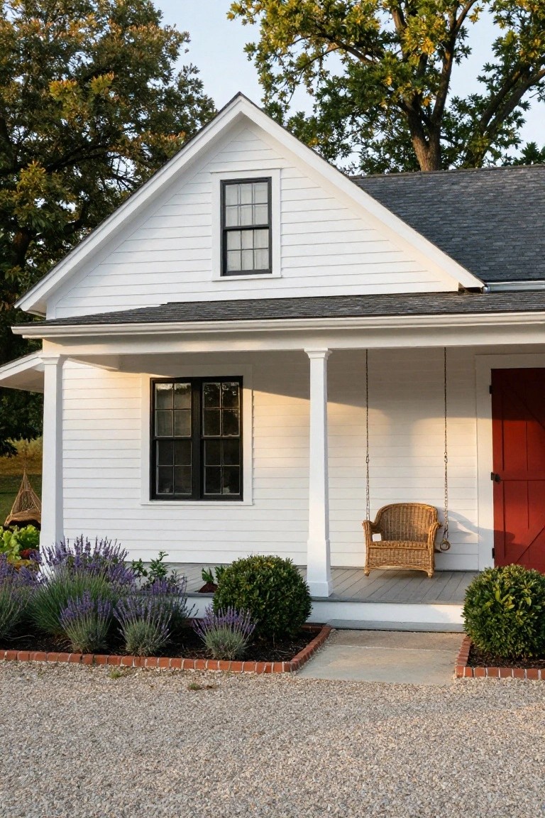 White cottage with red door, porch swing, and lavender garden.