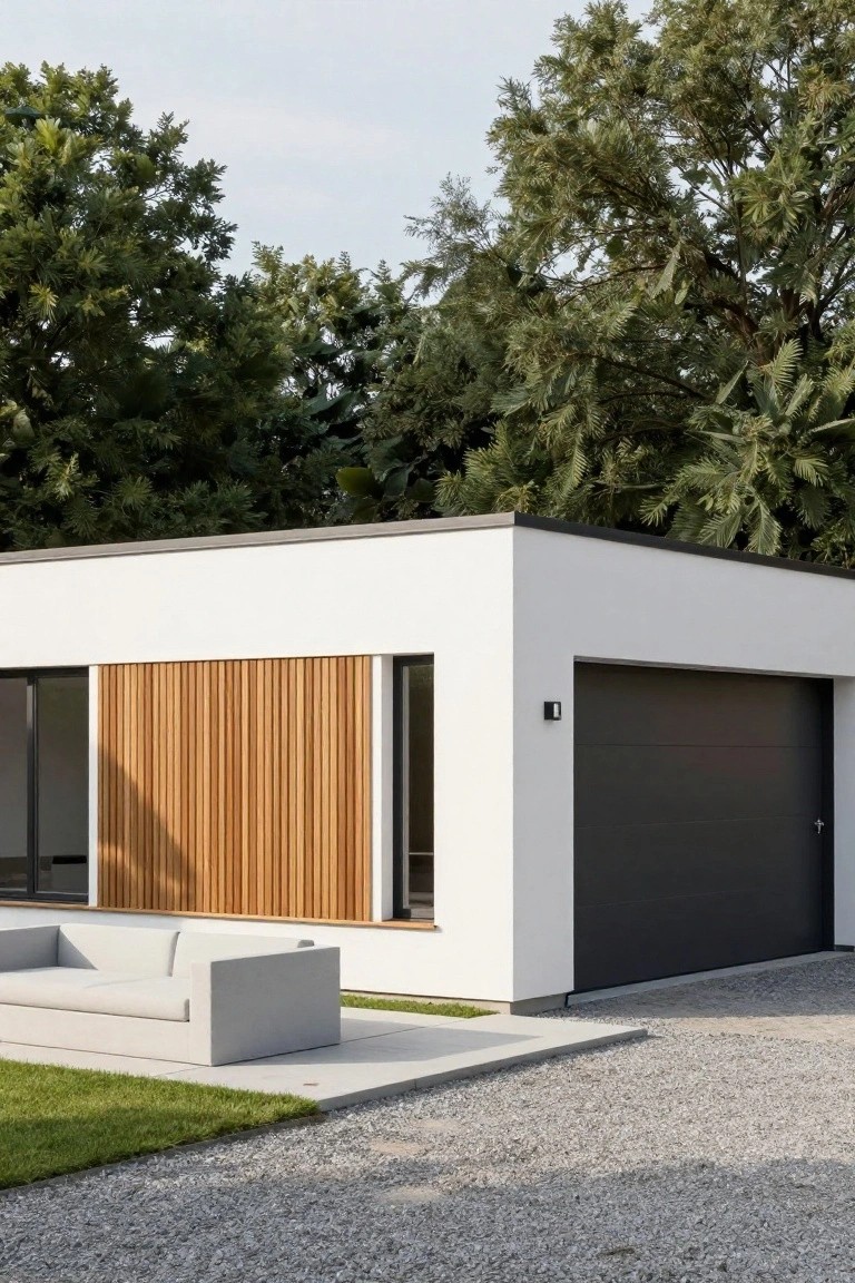 Modern white house corner with vertical wooden slats beside large glass windows, black garage door, concrete sofa on concrete patio adjacent to grass and gravel driveway, trees in background.