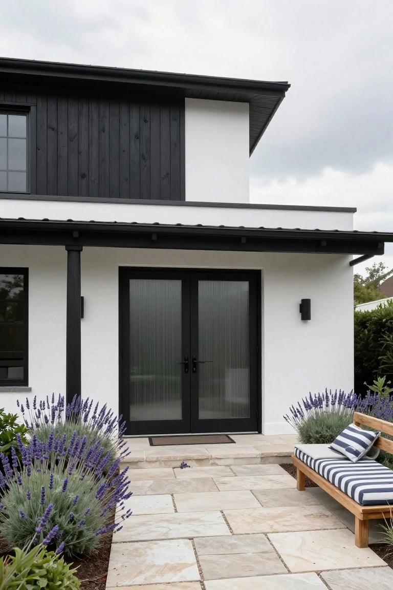 Modern white house with black doors, stone patio, lavender bushes, and striped bench