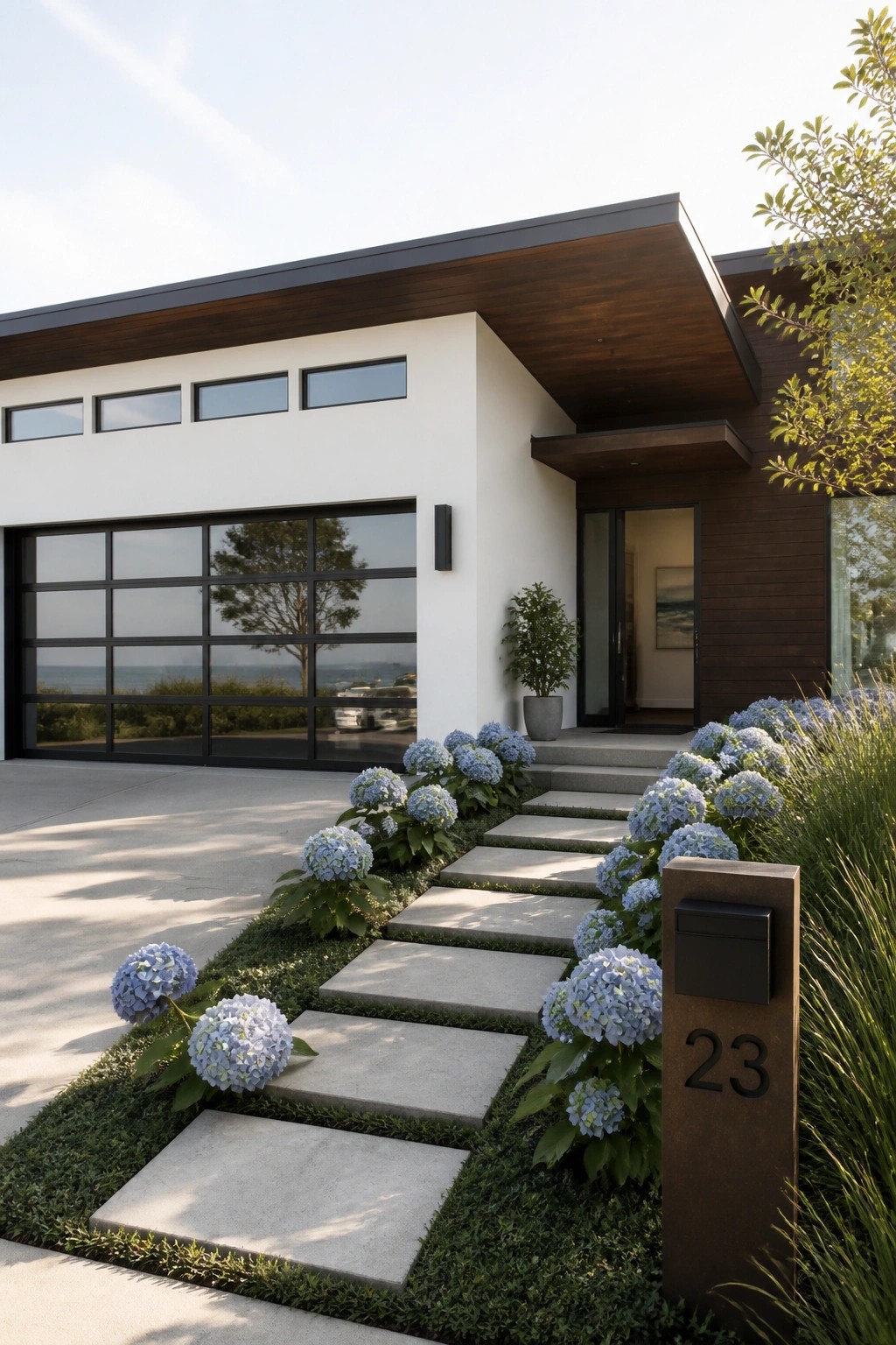 Modern white house with glass garage, hydrangea-lined stone path, and 23 mailbox.