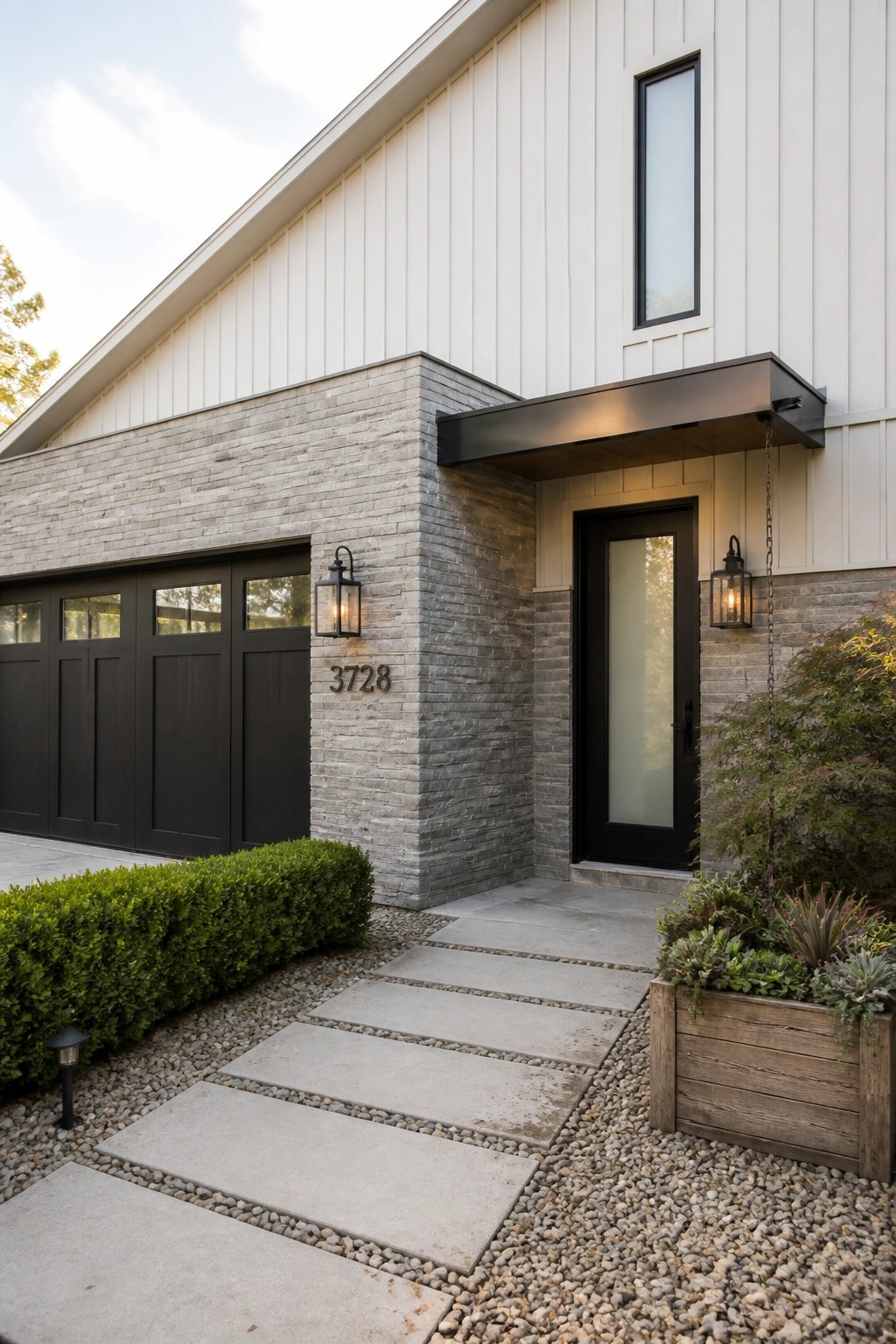Modern house exterior with white vertical siding, gray stacked stone on the lower wall sections around the garage and front door, black door and garage doors, and a concrete paver walkway on gravel.
