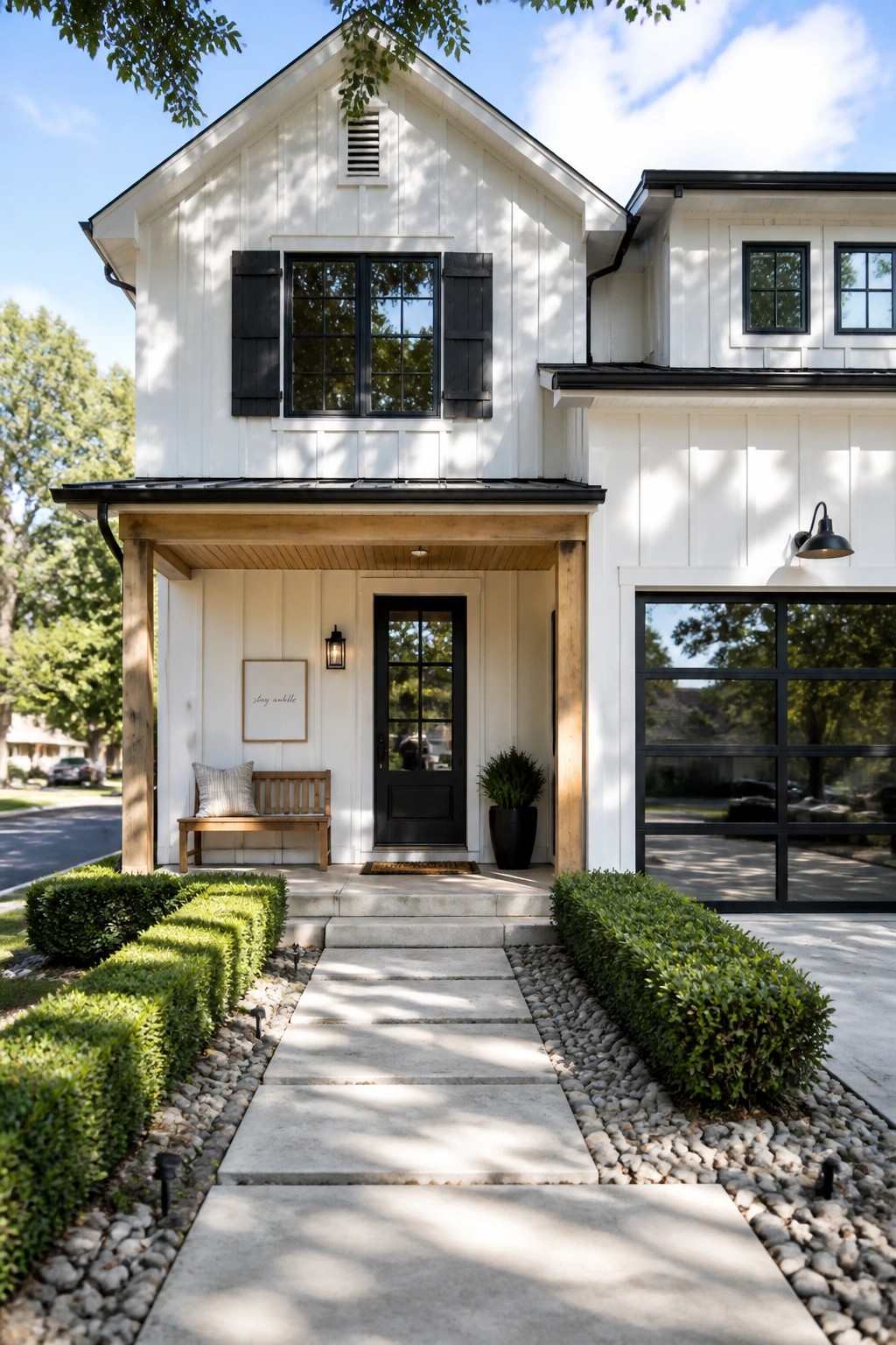 A two-story white house with black windows and shutters, a black front door, and a wood-framed front porch with a bench and potted plant.