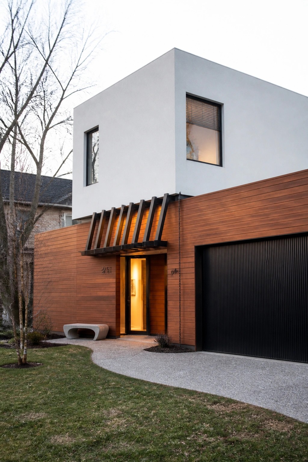 Modern two-story house exterior with white upper walls, horizontal wood cladding on the lower level, black garage door, and a geometric wood slat canopy over the front entrance.