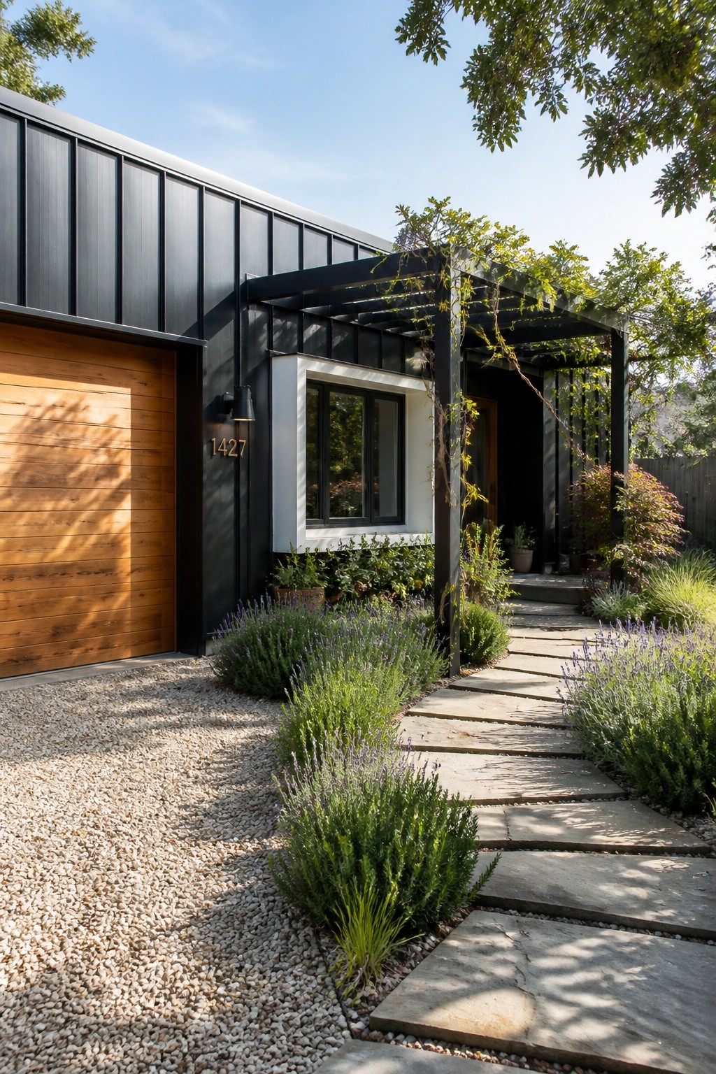 Modern black house with wood garage, stone path, and lush garden plants.