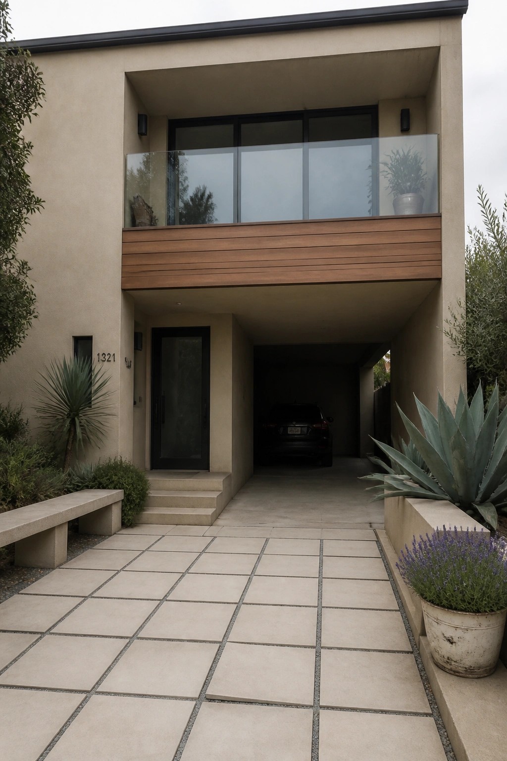Modern beige home with carport, black SUV, glass balcony, and desert plants.