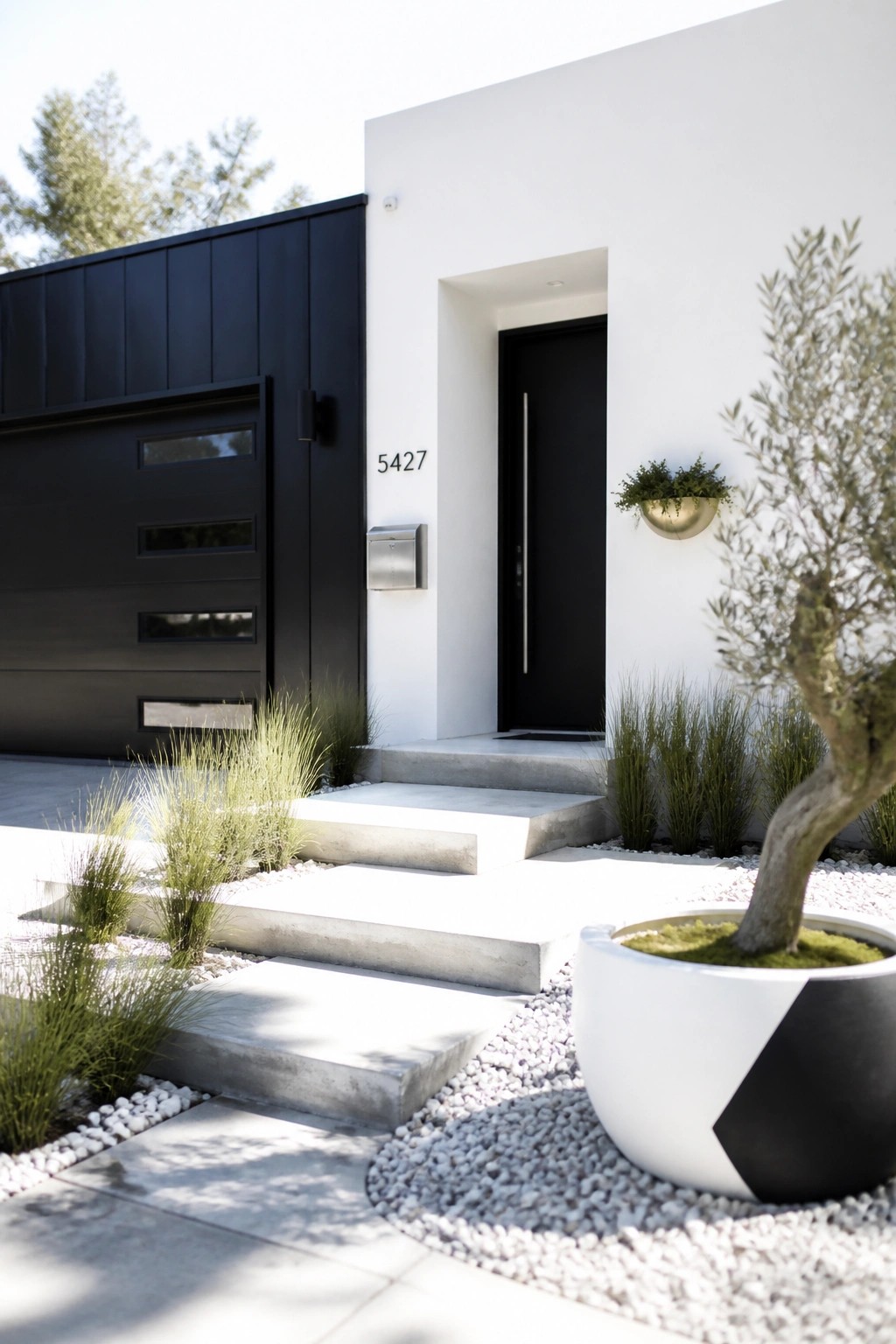 Modern white house with black door, concrete steps, gravel landscaping, and large potted tree.