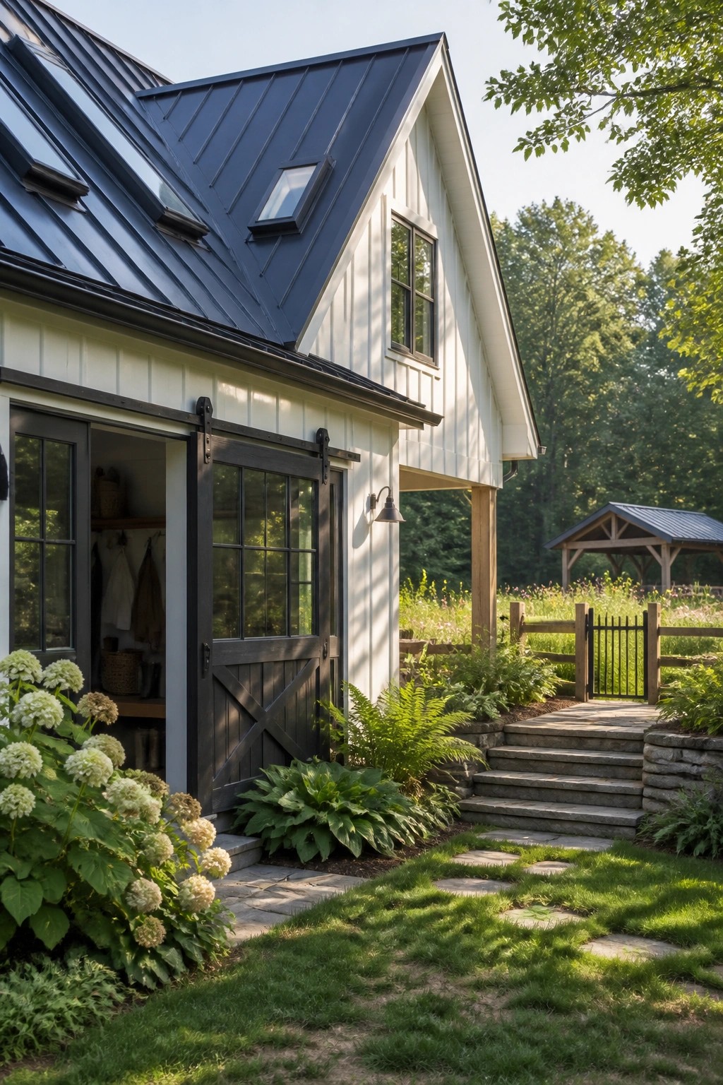 White farmhouse with dark metal roof, open barn door, stone path and garden