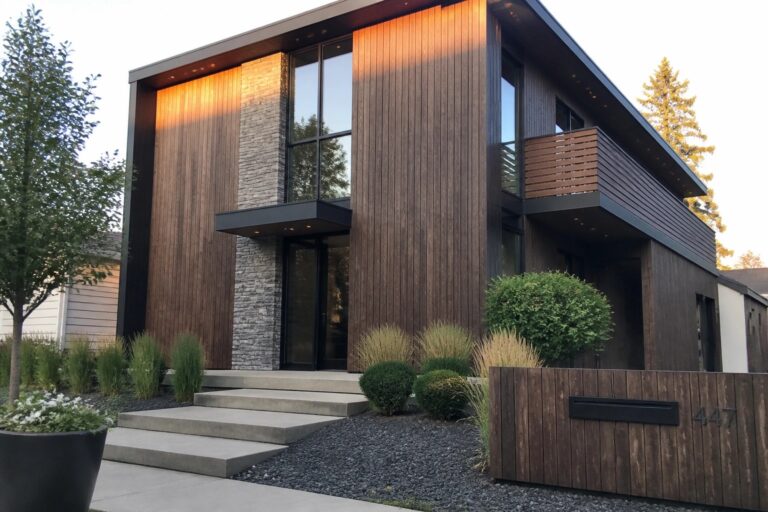20 Impressive Two-Story Luxury House Designs Emphasizing Vertical Facades A modern two-story house exterior featuring dark vertical wood siding, tall stacked windows, stone accents around the entry, and concrete steps leading to the front door.